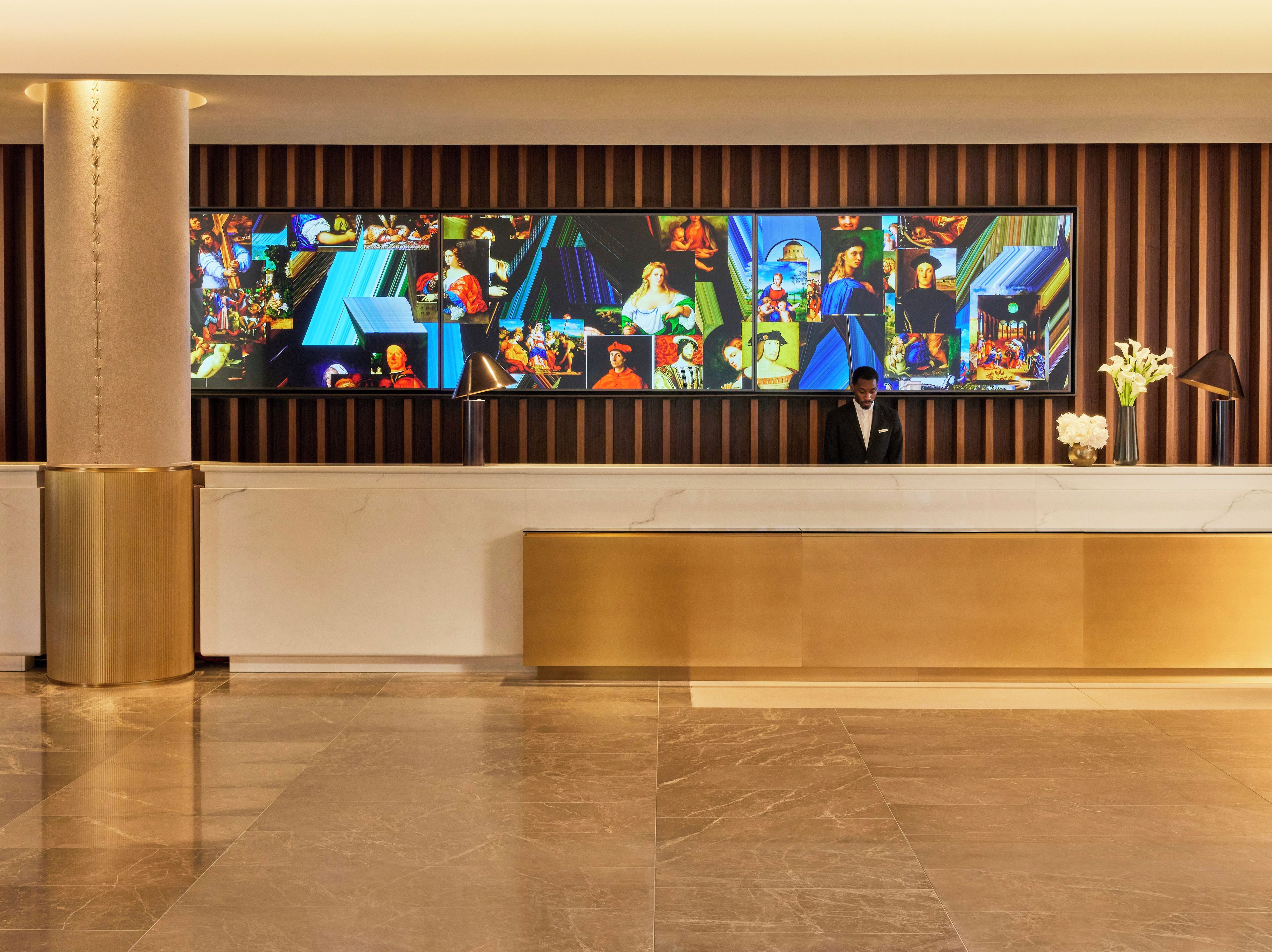 A reception area with a large digital art display, a reception desk, and a vase with flowers.