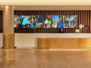 A reception area with a large digital art display, a reception desk, and a vase with flowers. - Omni Boston Hotel at the Seaport Artist Tower Experience (Boston)