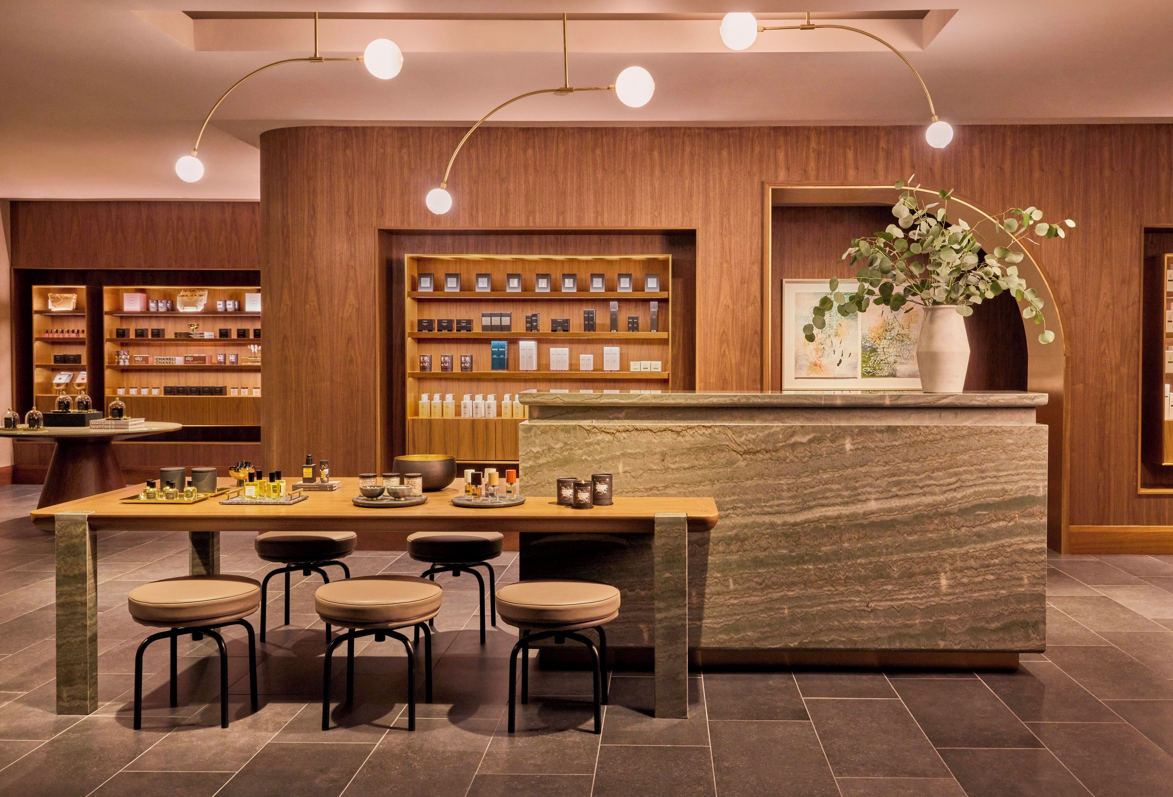 A modern lobby with a reception desk, seating area, and shelves displaying various products.