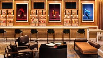 A bar area with multiple shelves of liquor bottles, bar stools, and a seating area with a sofa and chairs.