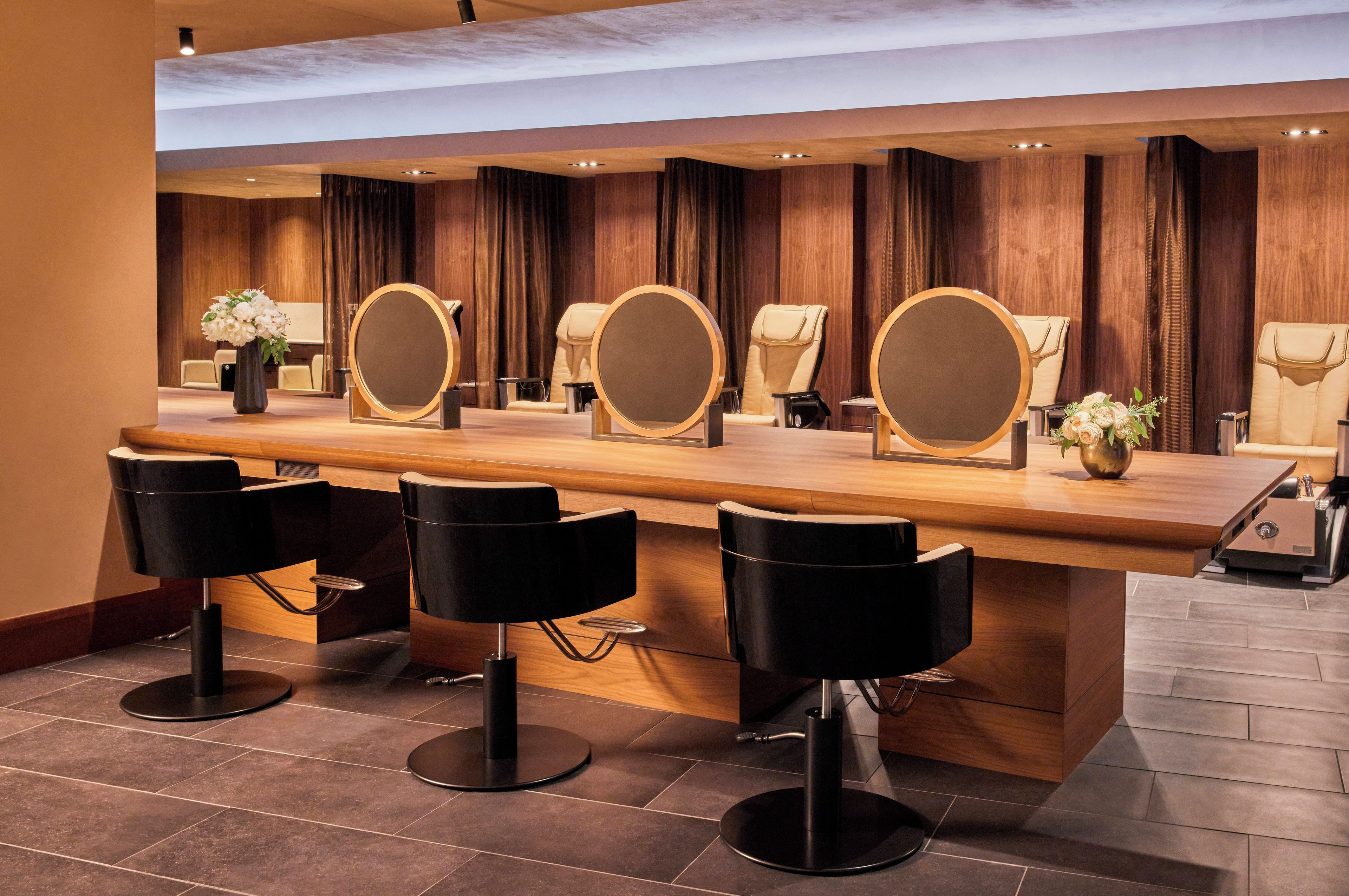 Een moderne bar met een houten toonbank, meerdere spiegels en zwarte barstoelen.