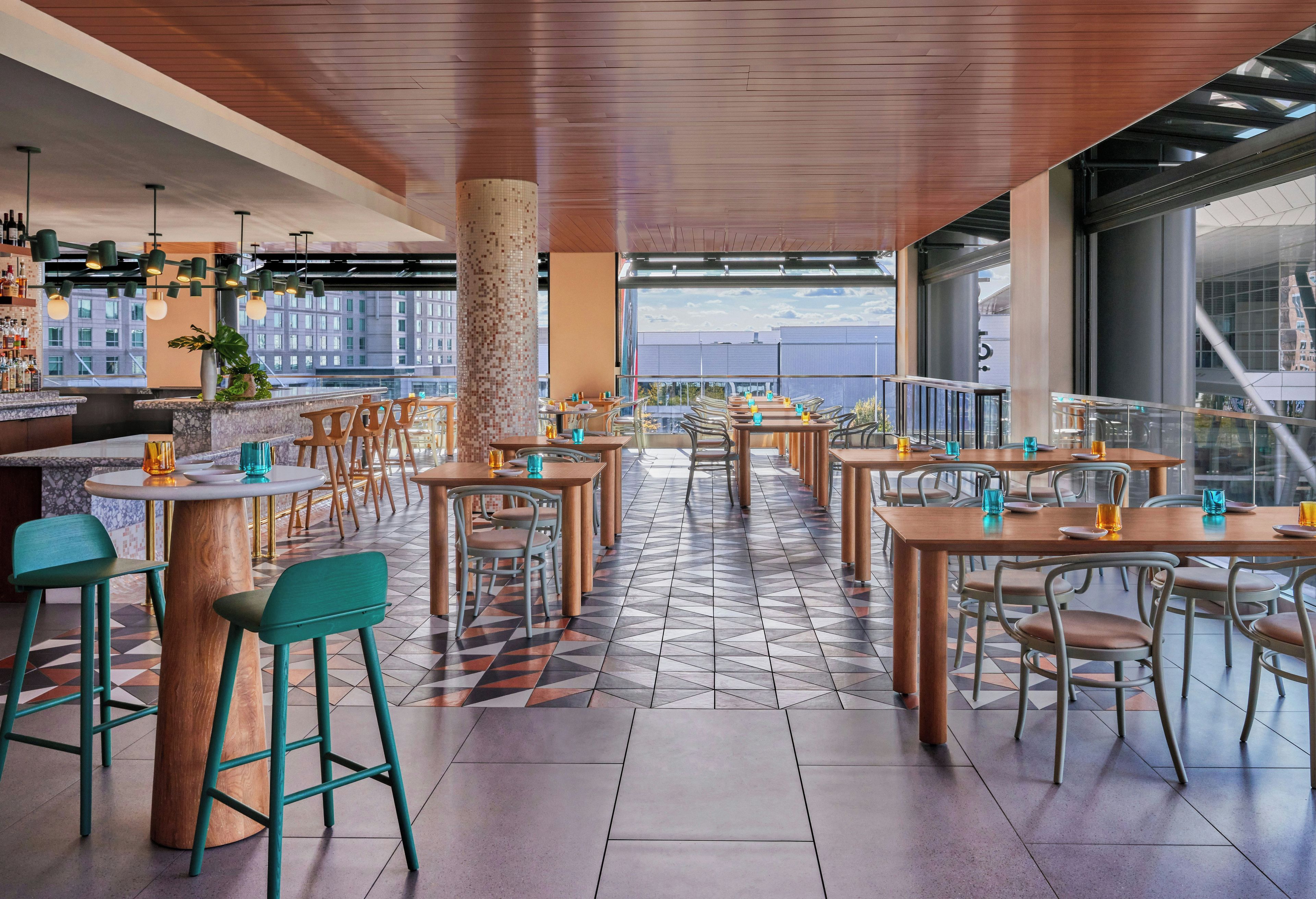 Un restaurante con terraza, varias mesas, sillas y una zona de bar.