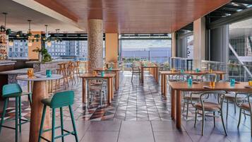 Un restaurante con terraza, varias mesas, sillas y una zona de bar.
