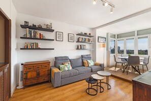 Una sala moderna con un sofá gris, un mueble de madera y estanterías.