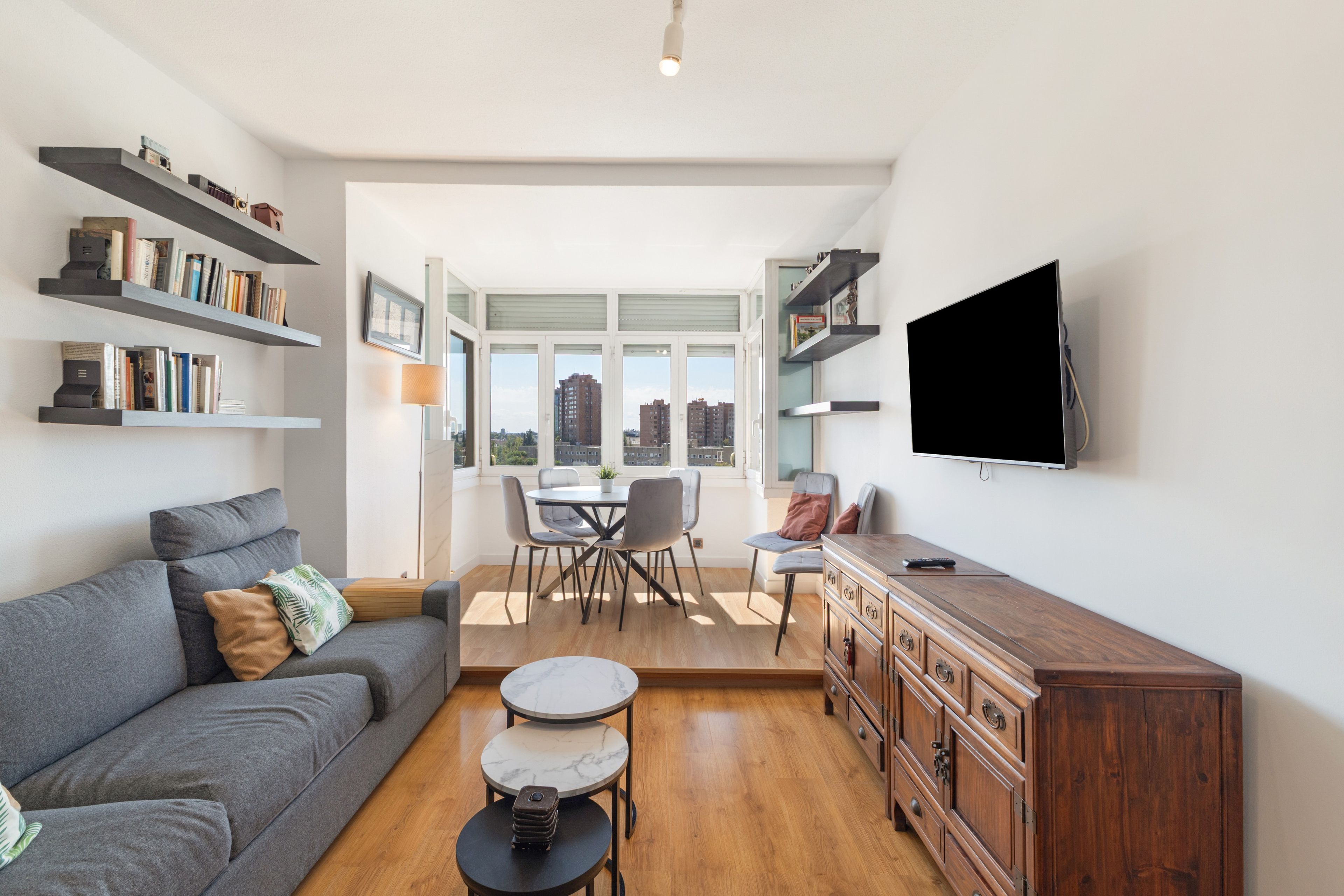 Una sala de estar moderna con sofá, mesa de centro, televisor y estanterías.