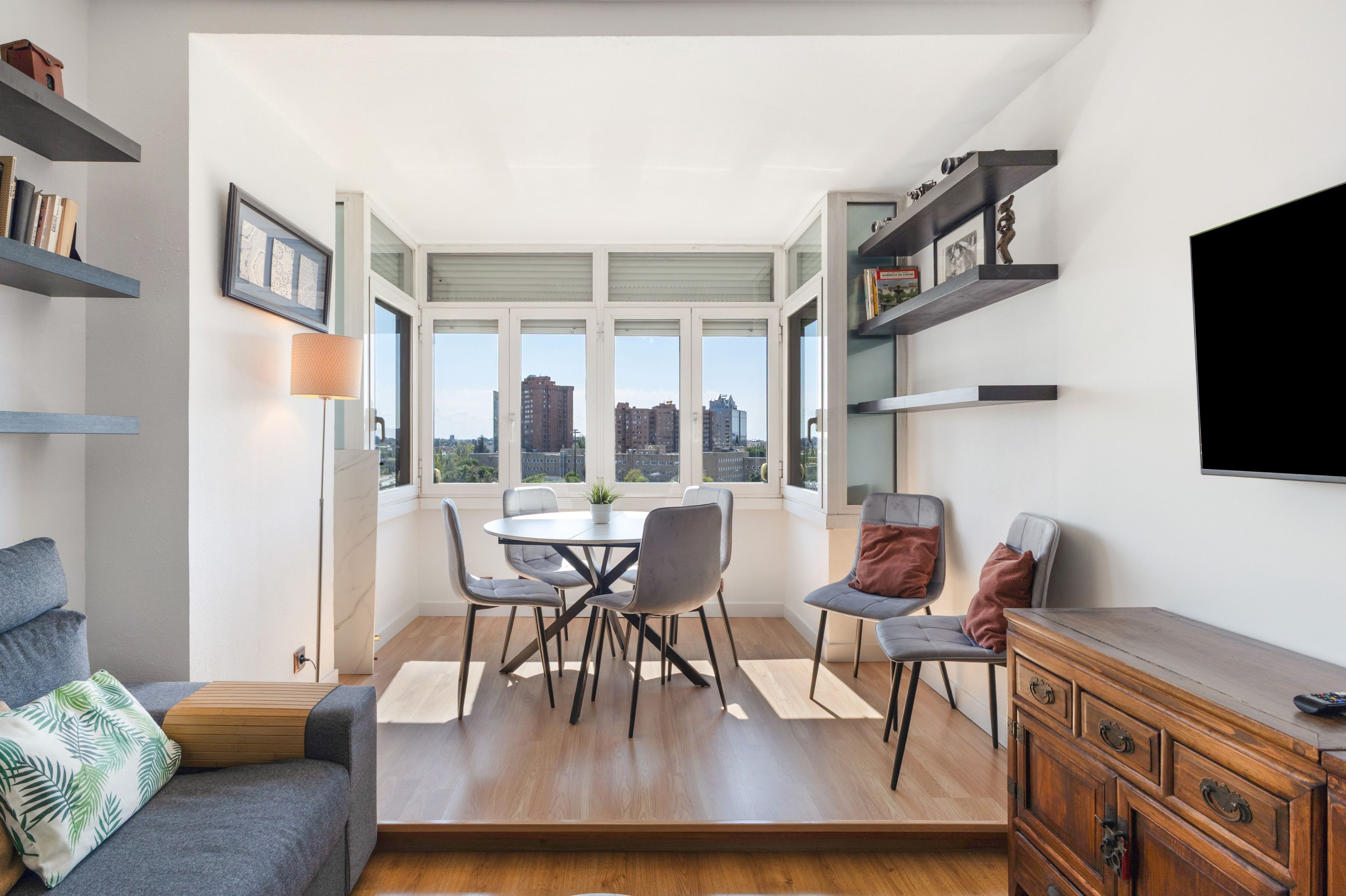 Una sala de estar moderna con comedor, ventanas amplias y vistas a la ciudad.