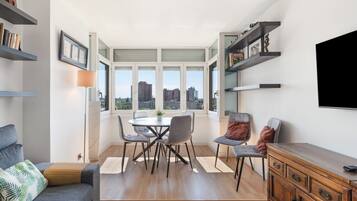 Una sala de estar moderna con comedor, ventanas amplias y vistas a la ciudad.