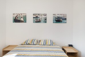 Un dormitorio con una cama, dos mesitas de noche y tres cuadros en la pared.