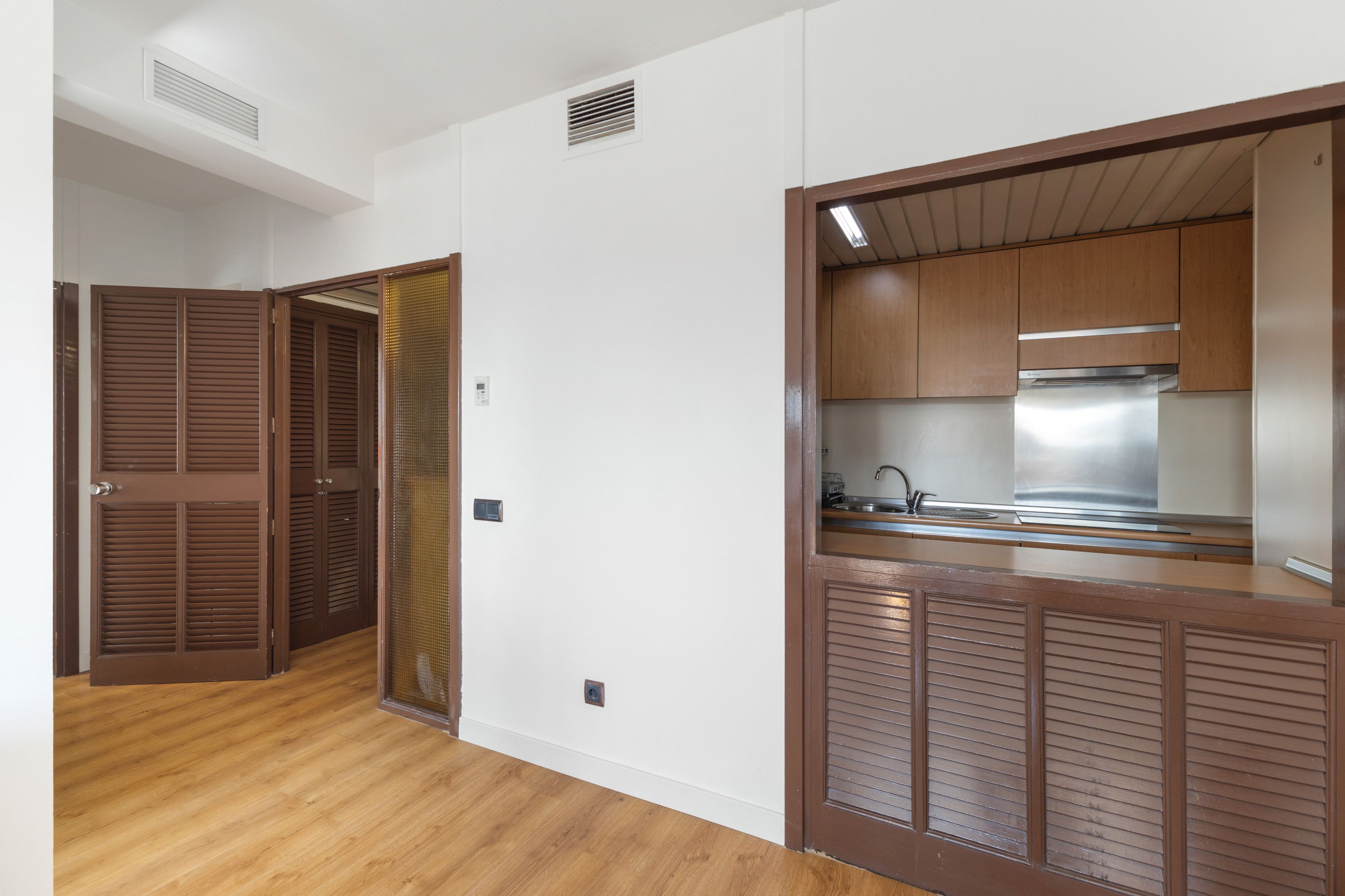 Een moderne keuken met houten kastjes, een roestvrijstalen afzuigkap en een inbouwspoelbak.