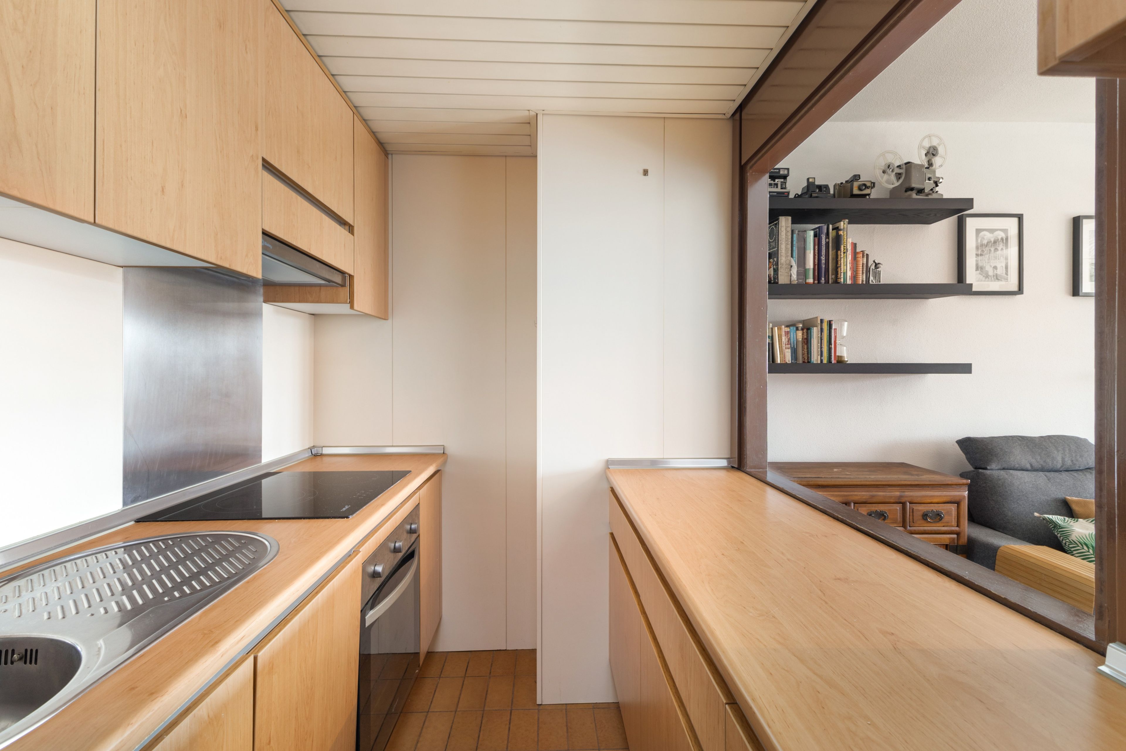 Una cocina moderna con armarios de madera, extractor de acero inoxidable y horno empotrado.