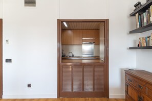 Cocina compacta con gabinetes de madera, extractor de acero inoxidable y pileta integrada.