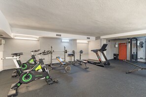 Un gimnasio con bicicletas estáticas, una cinta de correr y equipo de levantamiento de pesas.