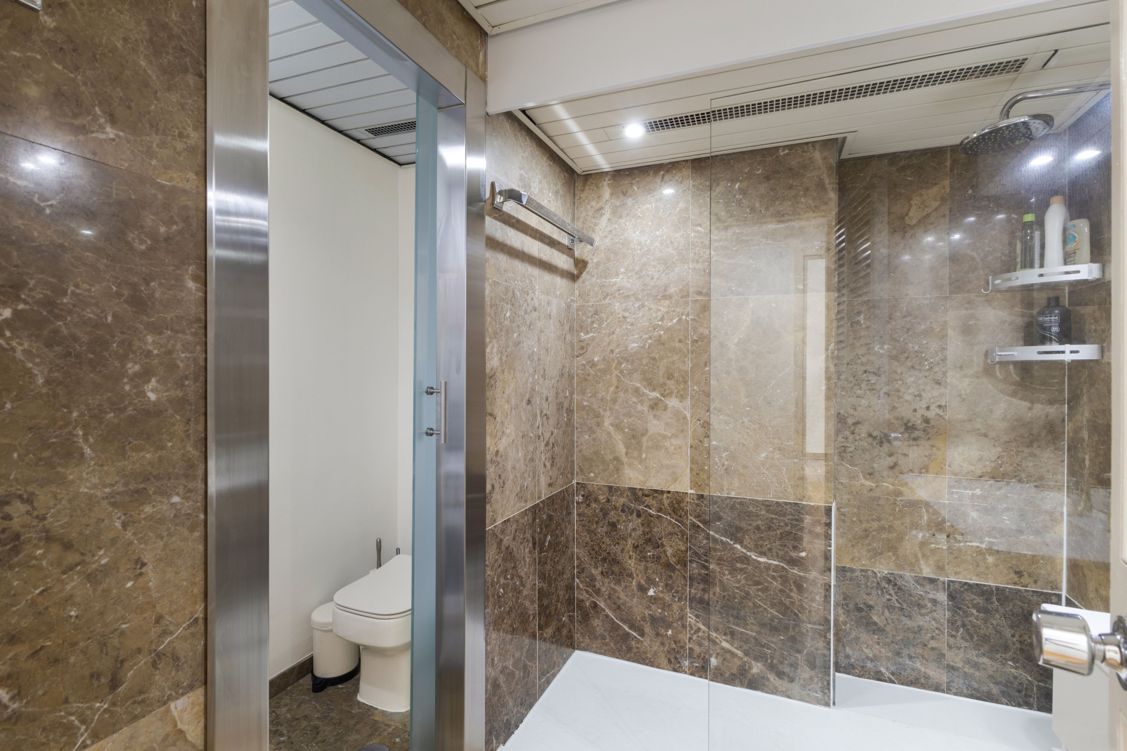 Un baño moderno con cabina de ducha de vidrio, inodoro y lavamanos.