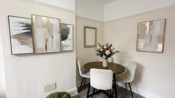 A dining area with a round table, four chairs, and three wall-mounted abstract paintings.