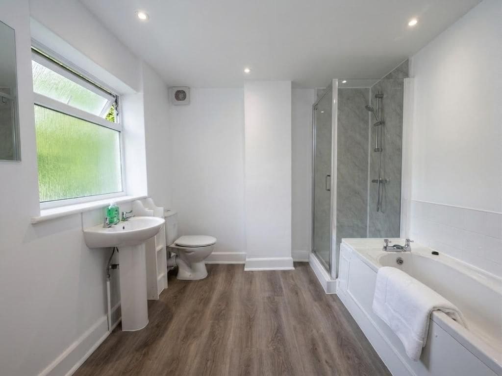 A modern bathroom with a shower, toilet, and sink.