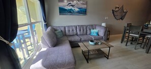 A living room with a grey sofa, a coffee table, and a dining area with chairs. - Hidden Gem One of Port A’s best-kept secrets (Port Aransas)