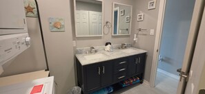 Une salle de bain avec un double vasque, des meubles sombres et un miroir au-dessus de la vasque.