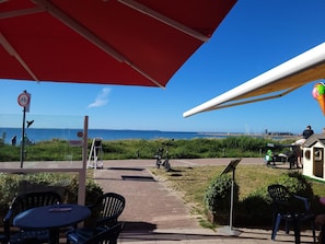 Un área de estar al aire libre con vista al mar, una sombrilla roja y un letrero de bicicletas.