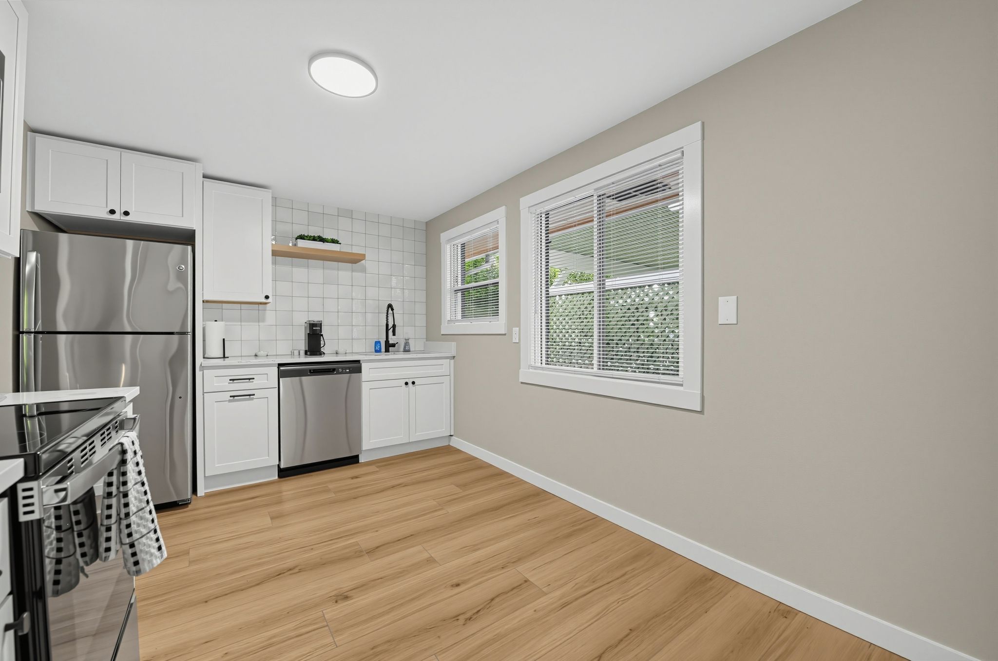 Una cocina moderna con armarios blancos, electrodomésticos de acero inoxidable y piso de madera.
