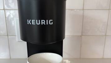 Eine Keurig-Kaffeemaschine mit einer weißen Tasse auf dem Sockel.
