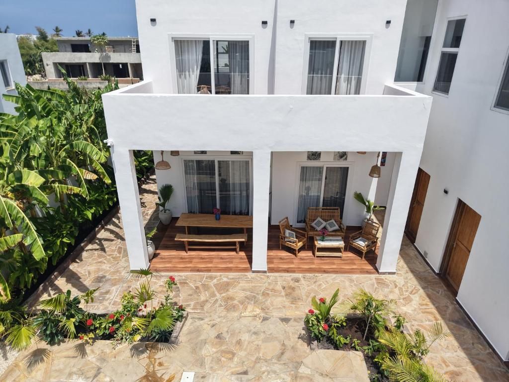 Un bâtiment à deux étages doté d’un patio comprenant un banc en bois et des meubles en osier.