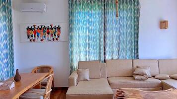 Una sala de estar con sofá, una mesa de comedor con sillas y una obra de arte colgada en la pared.