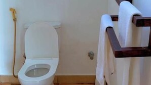 Pieni kylpyhuone, jossa on wc, puulattia ja pyyheteline.