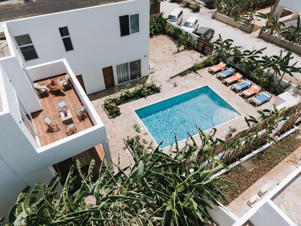 A modern building with a rooftop patio, a swimming pool, and lounge chairs.