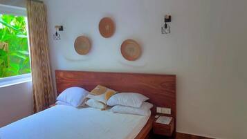 Un dormitorio con cabecera de madera, cama con ropa de cama blanca y mesita de noche con teléfono y lámpara.