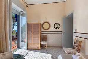 A room with a bed, a chair, a wardrobe, and a door.