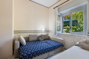 A small, cozy room with a single bed, a window with a view of greenery, and a patterned bedspread. - Villa Scogliera dei Gabbiani with sea view, shared pool and Wi-Fi (Scario)