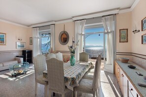 A dining area with a table set for two, a sofa, and a view of the sea. - Villa Scogliera dei Gabbiani with sea view, shared pool and Wi-Fi (Scario)