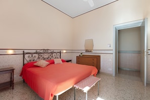 Un dormitorio con cama, mesitas de noche, cómoda, espejo y puerta.