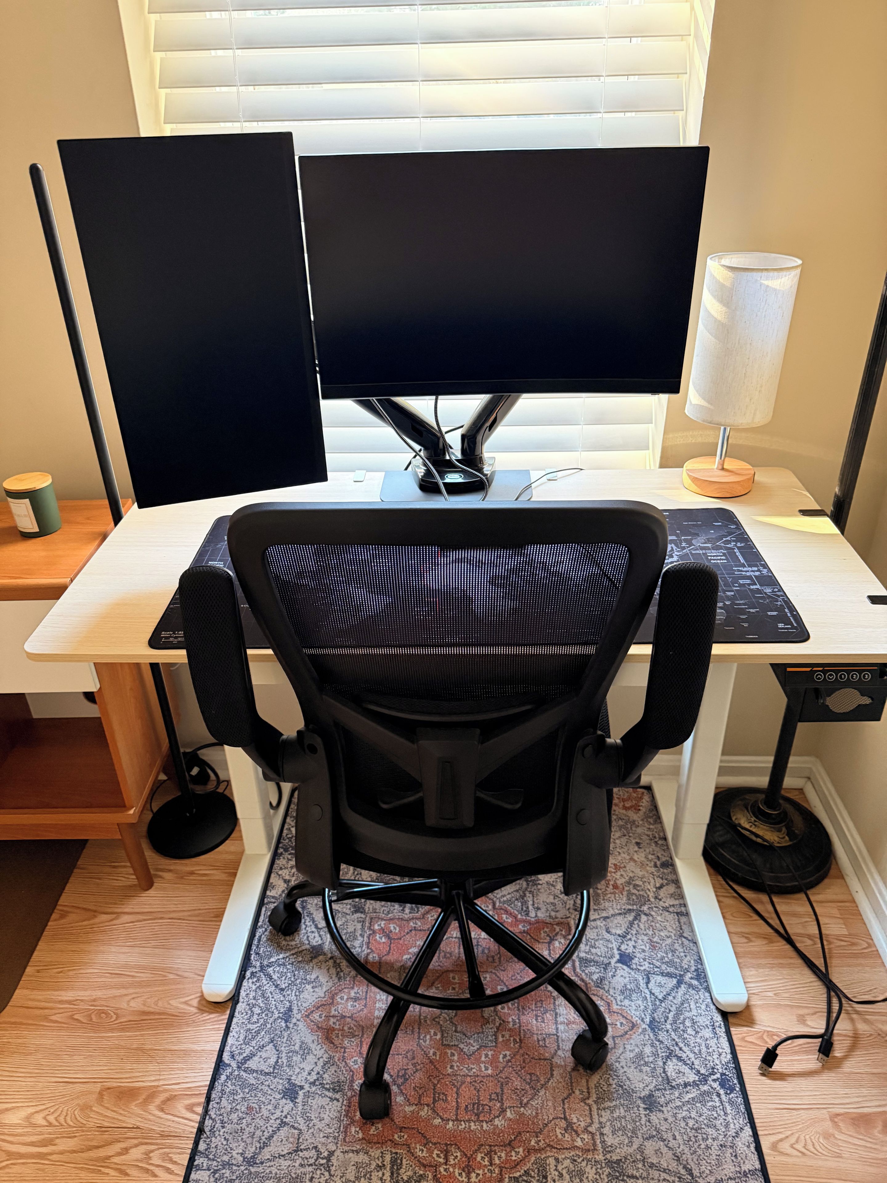 A workspace with a desk, two monitors, a chair, a lamp, and a keyboard.