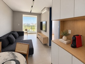 A modern living room with a sofa, a dining table, and a TV. - You Faria Lima (São Paulo)