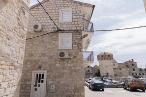 A stone building with a balcony and a tower in the background. - A2 - studio apartment near the beach with the sea view (Kaštel Gomilica)