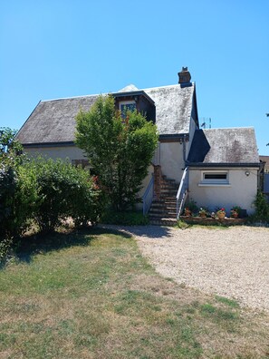 A house with a sloped roof, a visible chimney, a front door, and a small set of stairs leading to the entrance.
