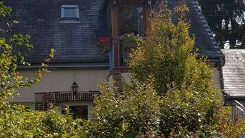A house with a sloped roof, a visible chimney, and a small balcony with flowers.