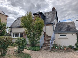 A two-story house with a brick chimney, a blue staircase, and a small window. - "First Floor" Apartment with Shared Garden, Wi-Fi, and Air Conditioning (Saint-Germain-sur-Avre)