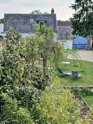 A residential property with a garden, outdoor seating, and a brick building.
