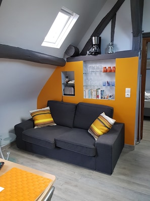 A modern living room with a sofa, a glass coffee table, and a bookshelf. - "First Floor" Apartment with Shared Garden, Wi-Fi, and Air Conditioning (Saint-Germain-sur-Avre)