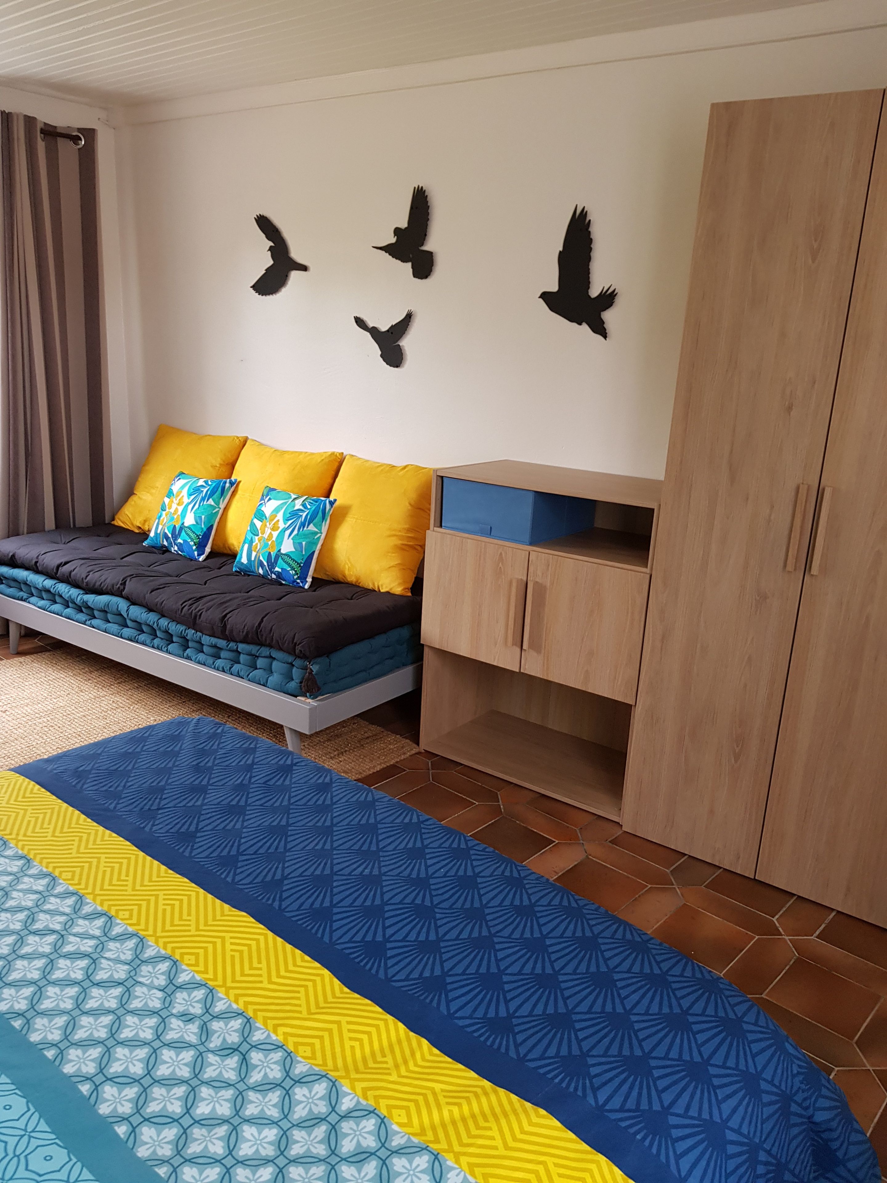 Ein Schlafzimmer mit Bett, Kleiderschrank, Schreibtisch und Wandbildern.