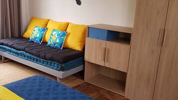Ein Schlafzimmer mit Bett, Kleiderschrank, Schreibtisch und Wandbildern.