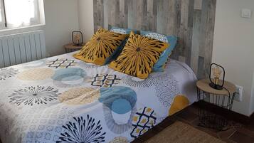 Een slaapkamer met een bed, een raam, een wand met houten panelen en een kleine tafel met een lamp.