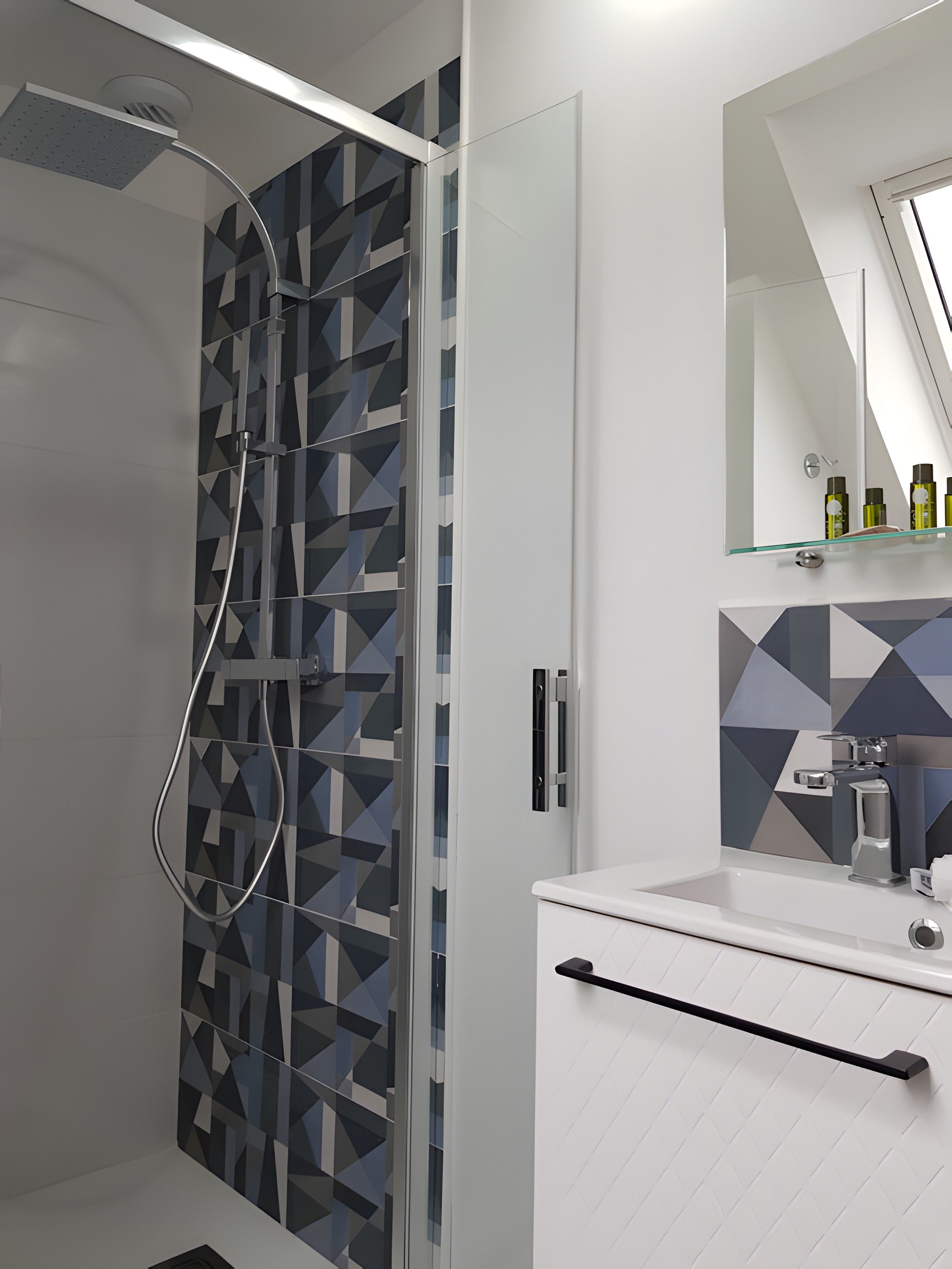 Une salle de bain moderne dotée d’une cabine de douche, d’une porte en verre et d’un meuble-lavabo avec un miroir.
