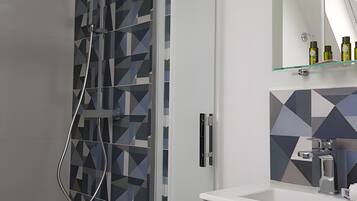 Une salle de bain moderne dotée d’une cabine de douche, d’une porte en verre et d’un meuble-lavabo avec un miroir.