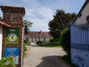 A gated entrance to a building with a brick facade, a gravel path leading to the entrance, and signage indicating 'Gite' and 'CHAMBRES D'HOTES.' - Guest Room "Chambre bleue - 1st Floor" with Shared Garden and Wi-Fi (Saint-Germain-sur-Avre)