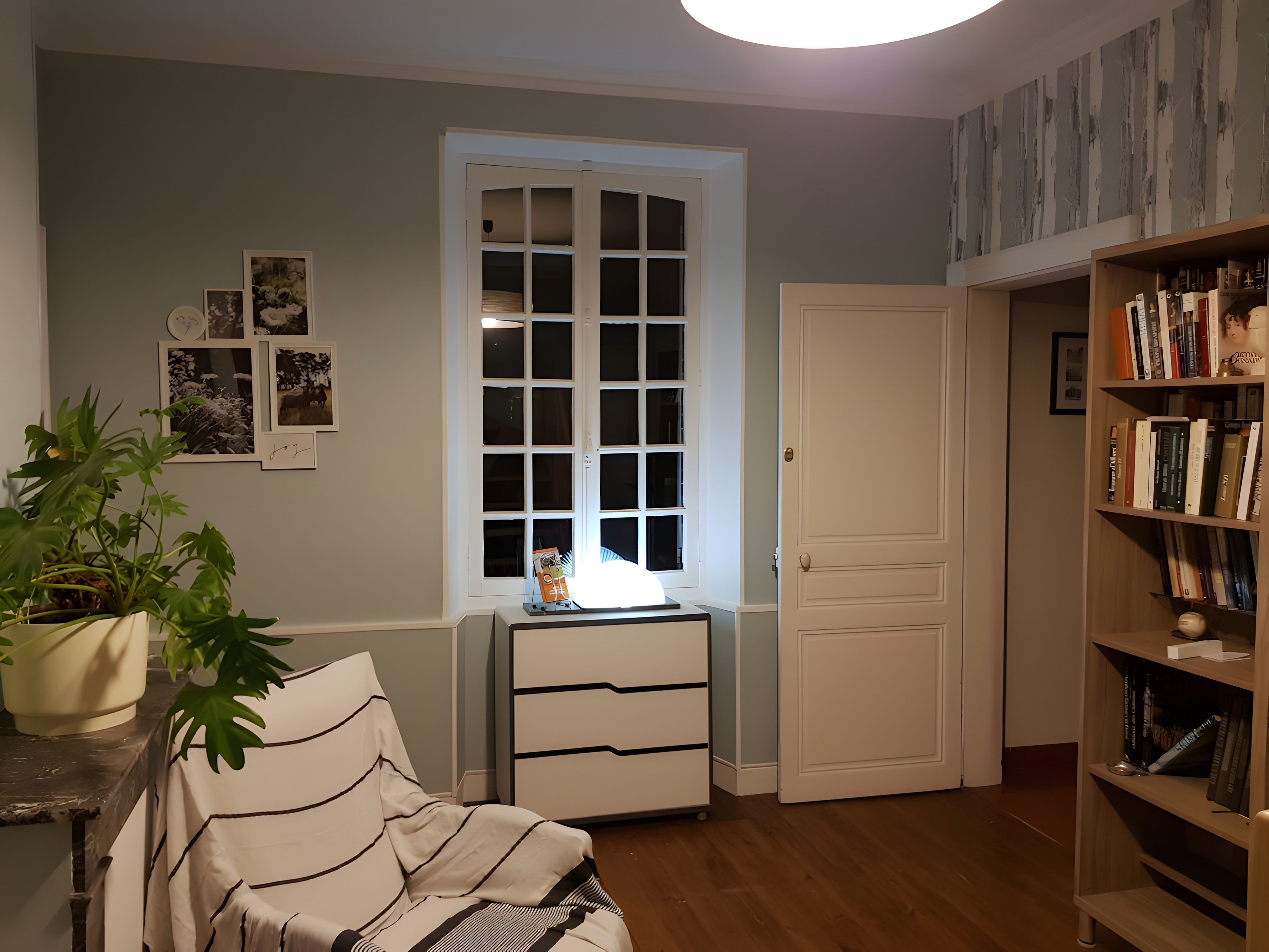 Een kamer met een bed, een bureau, een boekenkast, een raam en een deur.