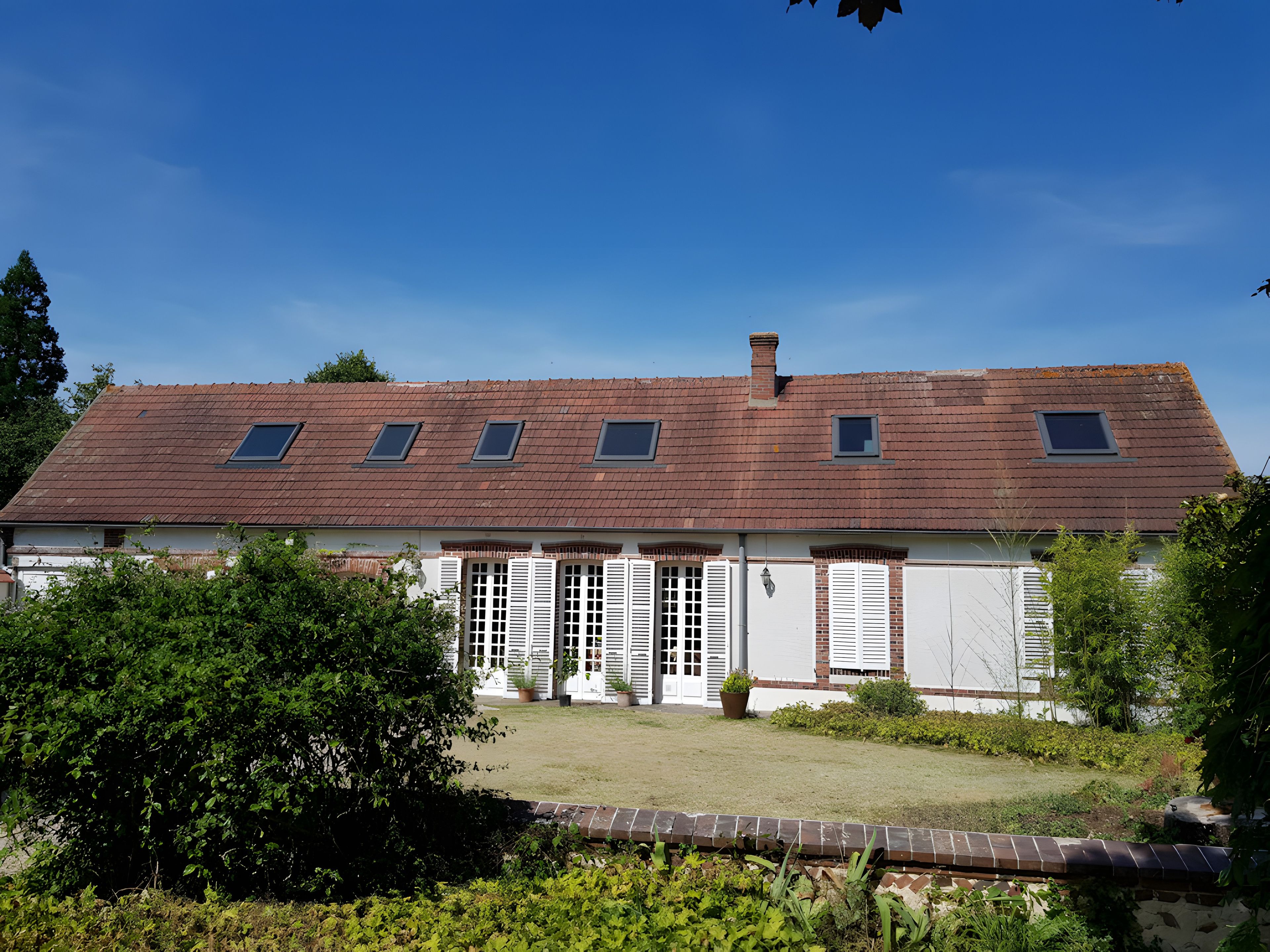 A two-story house with a sloped roof, dormer windows, and a front garden.