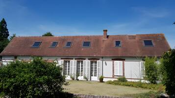 A two-story house with a sloped roof, dormer windows, and a front garden.
